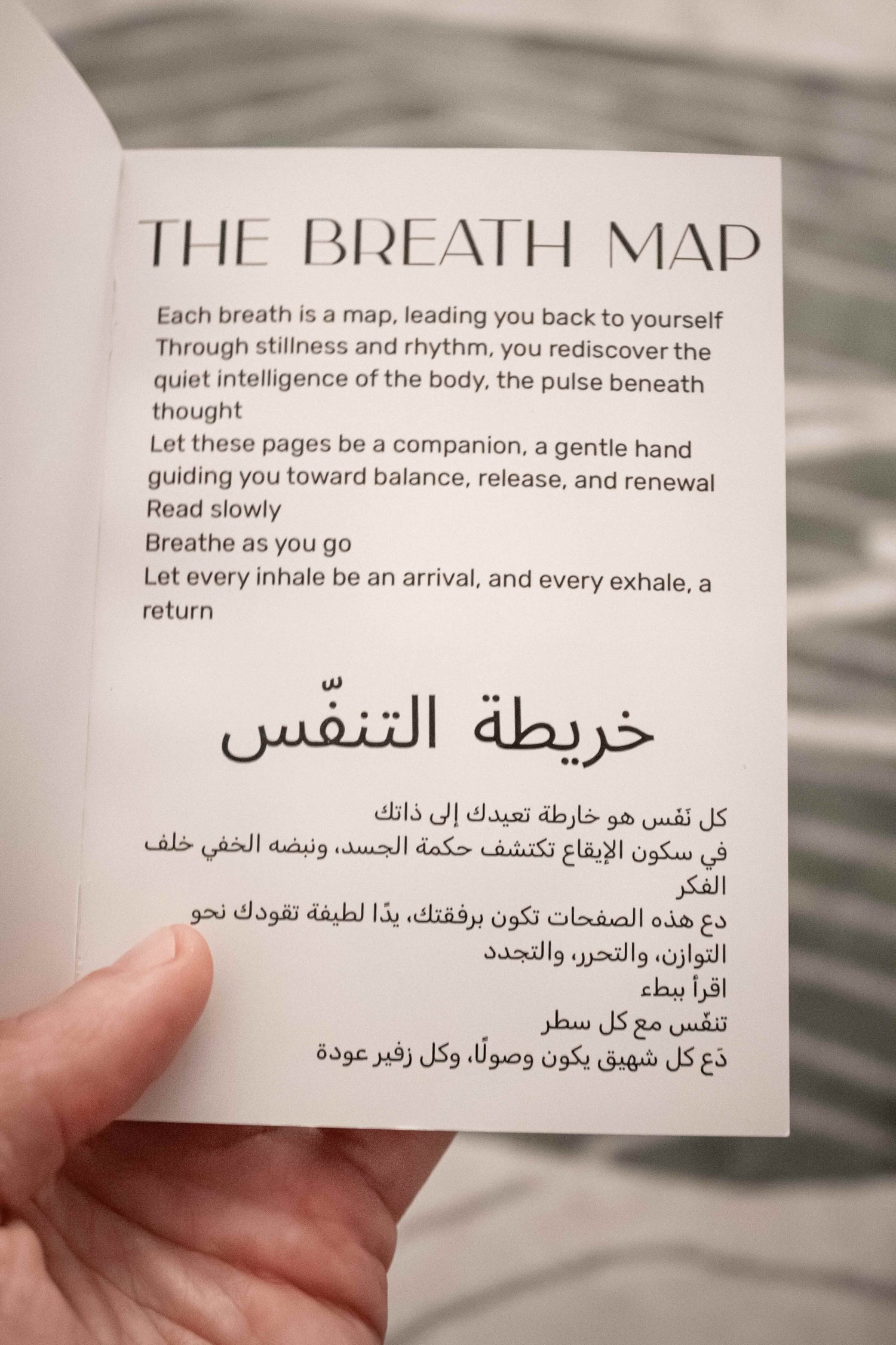 Open Nafas Breath Map booklet showing English and Arabic introduction about mindful breathing, held in hand.